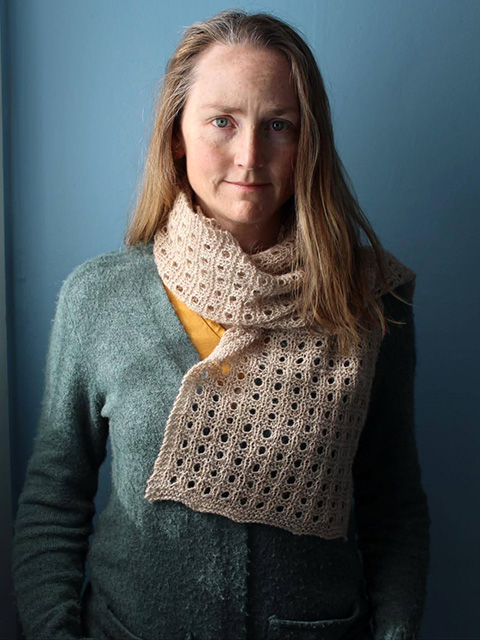 The photo depicts a white woman with shoulder-length light brown hair and is wearing a soft blue sweater and cream scarf.